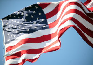 The image features the American flag blowing in the wind.